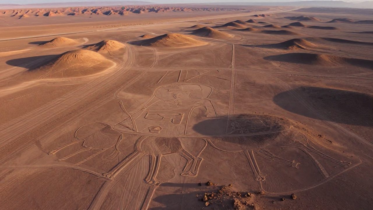 Vista aérea de los inmensos geoglifos antiguos grabados en el desierto árido de Palpa, Perú, bajo una luz dorada de atardecer.
